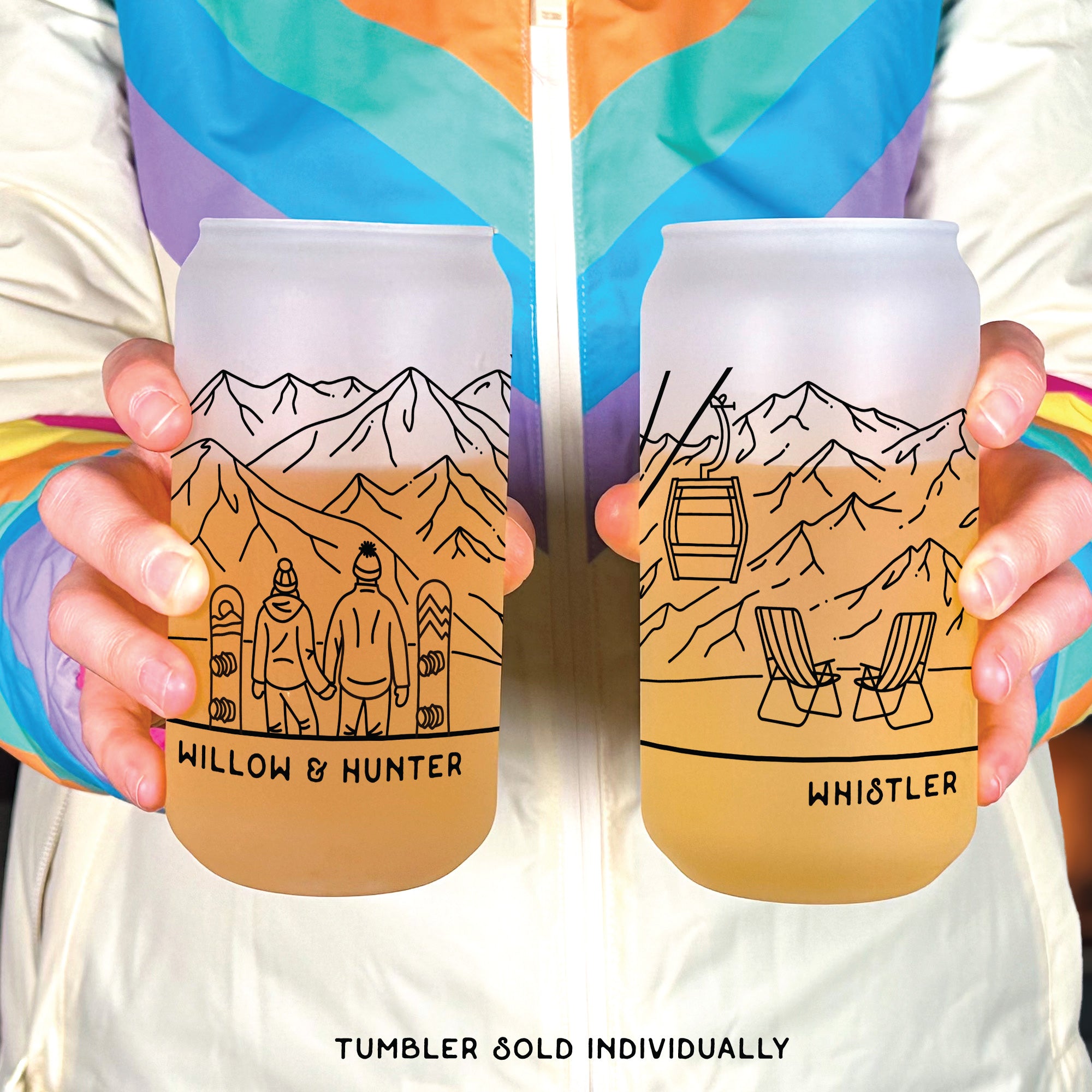 Hands holiding frosted glass tumblers. Tumbler design of snowboarding couple looking at winter mountain range. Text Willow & Hunter on the left under the couple. Text Whistler on the right under the ski lounge chairs.