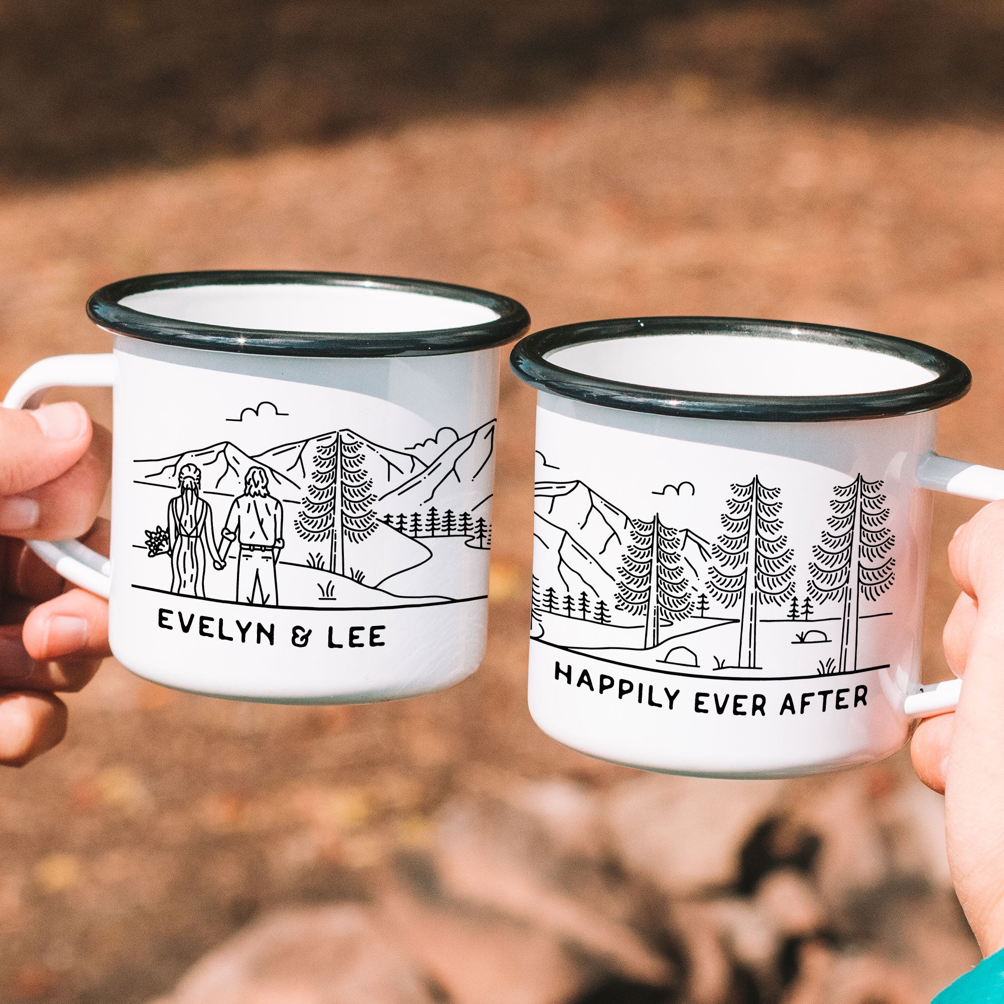 Hands holding two white enamel mugs with black rims. Text example: Evelyn & Lee (left side), Happily Ever After (right side)